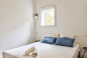 a white bed with blue pillows and a window at NOCNOC - Le Terrazzo - Petite piscine et jardin en ville in Montpellier