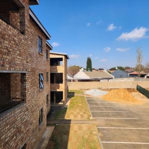 an empty parking lot next to a brick building at Two Bedroom townhouse THE PINES ALBERTSDAL in Alberton