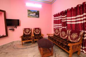 a living room with two chairs and a tv at Phoenix Holiday Home in Kanyakumari