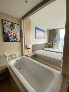 a bathroom with a large bath tub and a bed at Home Seview at Cam ranh Nha Trang Aparment in Cam Ranh