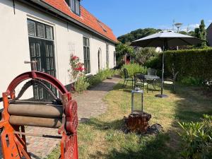 un jardín con mesa y sombrilla en B&B Wasboerderij Beek Ubbergen, en Beek