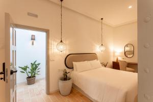 um quarto com uma cama branca e dois vasos de plantas em Albariza Hotel Boutique em Sanlúcar de Barrameda