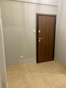 Una puerta de madera en una habitación con suelo de baldosa. en Cozy flat Korydallos, en Pireo