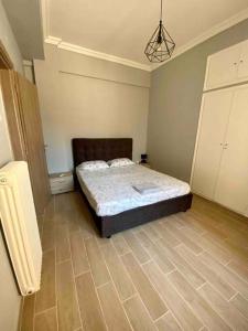 1 dormitorio con 1 cama y suelo de madera en Cozy flat Korydallos en Piraeus