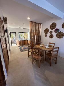 uma sala de jantar com uma mesa de madeira e cadeiras em Maracuja villa Zanzibar em Bwejuu