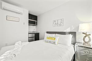 Dormitorio blanco con cama blanca grande y almohada amarilla en Sunset Inn-South Miami, en South Miami