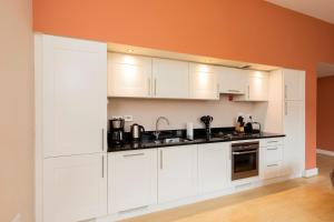 a kitchen with white cabinets and an orange wall at Cloister View in Fort Augustus