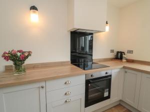 a kitchen with white cabinets and a black appliance at Gudhjem in Seahouses