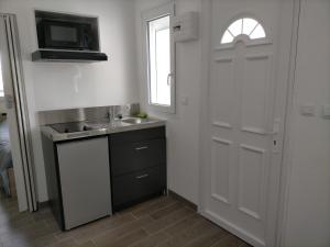 a kitchen with a sink and a microwave and a door at Beau studio indépendant à15mn de la plage, proche de toute commodité in Béziers