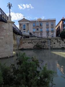 un ponte su un fiume di fronte a un edificio di Panoche Apartamento a 750m de la Catedral A/A a Murcia