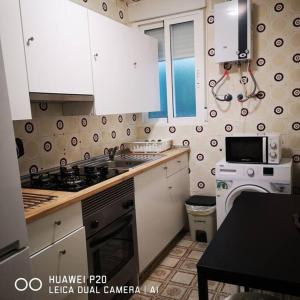 una cucina con mobili bianchi e un forno a piano cottura di Panoche Apartamento a 750m de la Catedral A/A a Murcia