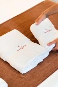 una persona che tiene due asciugamani bianchi su un tavolo di Double Room, attached bathroom - Casa del Indiano a La Orotava