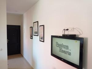 a flat screen tv on a white wall with pictures at maison Halima in Ifrane