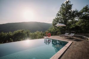 una piscina con 2 sillas y una sombrilla en Agriturismo Casa Augusta, en Castiglion Fibocchi