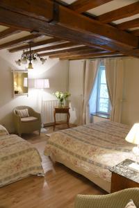a bedroom with two beds and a chair at Domaine de l'Ermitage in Berry-Bouy