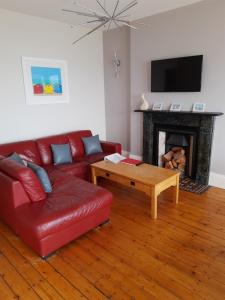 a living room with a red couch and a fireplace at Snooze Apartments in Newcastle