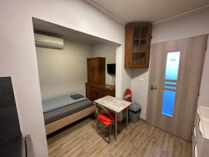 a small room with a bed and a table and a door at Beregi Apartman in Tiszaújváros