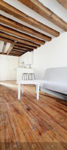 a white bed in a room with a wooden floor at Attrayant studio tout équipé en Bord de Marne - Proche Disney in La Ferté-sous-Jouarre