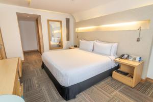 una camera d'albergo con un grande letto e uno specchio di Sonesta Hotel Bogotá a Bogotá