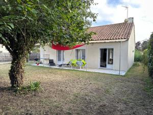 ein kleines weißes Haus mit einem Tisch und Stühlen im Hof in der Unterkunft 100 M DE LA PLAGE 100 DU BOURG DES MOUTIERS EN RETZ in Les Moutiers