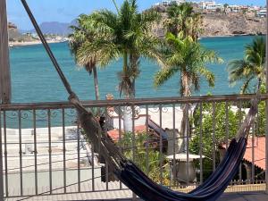uma rede de descanso numa varanda com palmeiras e o oceano em Vista al mar y alberca privada en Sector Bahía em San Carlos