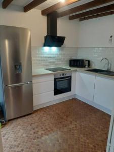 eine Küche mit einem Kühlschrank aus Edelstahl und weißen Schränken in der Unterkunft La Perle Marine in Le Vivier-sur-Mer