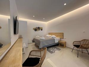a bedroom with a bed and chairs in a room at Anemos Apartments in Ornos