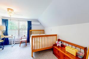 South Thomaston的住宿－Pleasant Beach Road Retreat，一间卧室配有一张婴儿床、一张桌子和一张书桌。