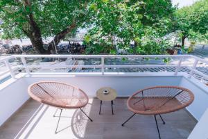 2 Stühle und ein Tisch auf einem Balkon mit Bäumen in der Unterkunft Vallia Suites-Green Luxury Suite A3 in Nafpaktos