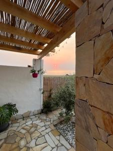 patio z kamienną ścianą i drewnianą pergolą w obiekcie Il Tramonto w mieście Giba