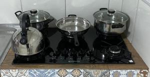 three pots and pans sitting on a stove top at Mirante Flat Triunfo in Triunfo