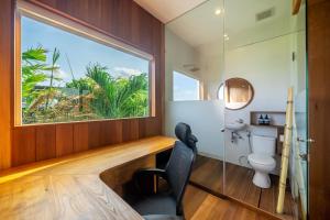 a bathroom with a window and a desk and a toilet at ZenDen Wellness Guesthouse in Canggu