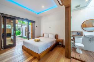 a bedroom with a white bed and a bathroom at ZenDen in Canggu