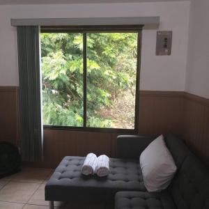 zwei Hausschuhe auf einer Couch vor einem Fenster in der Unterkunft Loft Near Airport, in Alajuela dowtown in Alajuela
