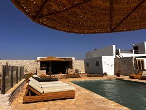 a resort with a swimming pool and an umbrella at Villa Madame BABOUCHE - Maison Beldi avec piscine in Ghazoua