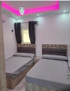 duas camas num quarto com iluminação rosa em SELENA BAY RESORT HURGHADa em Hurghada