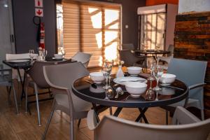 un comedor con mesas y sillas y copas de vino en Ranks Guesthouse, en Molepolole