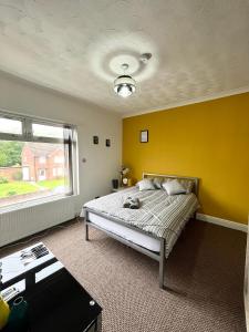 ein Schlafzimmer mit einem Bett und einer gelben Wand in der Unterkunft THE PORT House in Birmingham