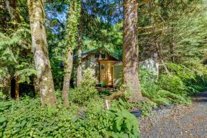 una cabaña en el bosque con árboles en Enchanting Arch Cape Retreat with Hot Tub, Fireplace, en Arch Cape