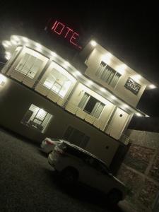 a white car parked in front of a hotel at night at Ihram Hotel And Guest House in Swat