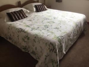 Una cama con una manta blanca con flores. en Albertine, en Lymington