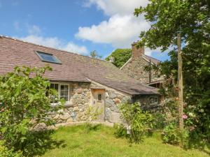 ein altes Cottage aus Stein mit einem Garten davor in der Unterkunft Beudy'r Wennol in Caernarfon