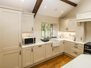 a kitchen with white cabinets and a microwave at Beudy'r Wennol in Caernarfon