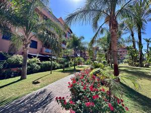 uma passarela num parque com palmeiras e flores em Dos Mares Apartamentos Playa Granada em Motril