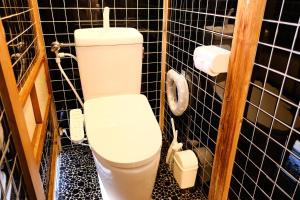 a white toilet in a black tiled bathroom at Forest-inn Kasama in Kasama +20 photos