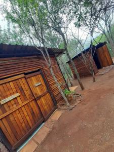a house with two wooden garage doors and trees at Impala trailor tent in Thabazimbi