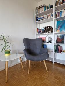 a chair and a table in a room with bookshelves at Big room with balcony in a shared apartment in the center of Kerava in Kerava