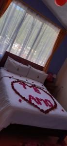 ein Bett mit einem Herz, das vor einem Fenster darauf gezeichnet ist in der Unterkunft Hosteria Llanovientos in Baños
