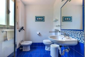 a blue and white bathroom with a sink and a toilet at Villa Le Tre Palme in Porto Azzurro