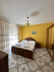 um quarto com uma cama e uma parede amarela em Dea Apartment em Berat